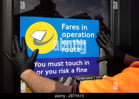 Busmitarbeiter installieren Aufkleber auf einem Bus in der Twickenham Busgarage, um Kunden daran zu erinnern, dass die Fahrpreise auf der Strecke während der COVID-19 pandemi in Betrieb sind Stockfoto