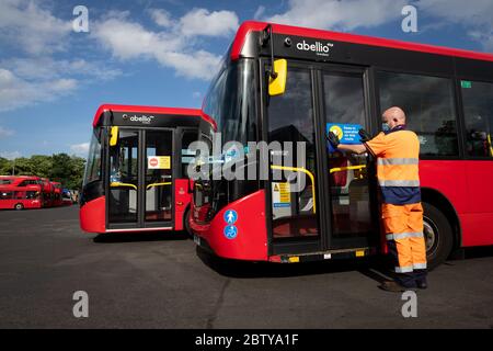 Busmitarbeiter installieren Aufkleber auf einem Bus in der Twickenham Busgarage, um Kunden daran zu erinnern, dass die Fahrpreise auf der Strecke während der COVID-19 pandemi in Betrieb sind Stockfoto