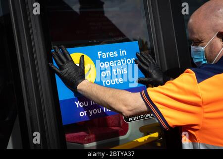 Busmitarbeiter installieren Aufkleber auf einem Bus in der Twickenham Busgarage, um Kunden daran zu erinnern, dass die Fahrpreise auf der Strecke während der COVID-19 pandemi in Betrieb sind Stockfoto