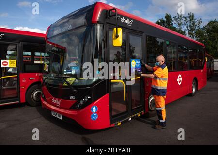 Busmitarbeiter installieren Aufkleber auf einem Bus in der Twickenham Busgarage, um Kunden daran zu erinnern, dass die Fahrpreise auf der Strecke während der COVID-19 pandemi in Betrieb sind Stockfoto