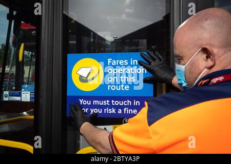 Busmitarbeiter installieren Aufkleber auf einem Bus in der Twickenham Busgarage, um Kunden daran zu erinnern, dass die Fahrpreise auf der Strecke während der COVID-19 pandemi in Betrieb sind Stockfoto