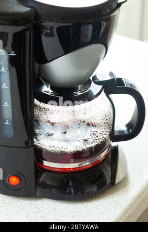 Nahaufnahme einer Kunststoff-Kaffeemaschine, die ein frisches Gebräu zubereitet. Stockfoto