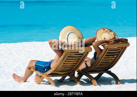 Pärchen liegen in Liegestühlen am Strand, auf den Malediven, im Indischen Ozean, Asien Stockfoto