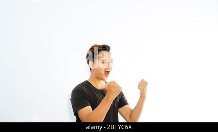 Der Asiate hob seine Hand auf der linken Seite und feierte und sagte ja. Konzept mit Wettbewerbsieg Stockfoto