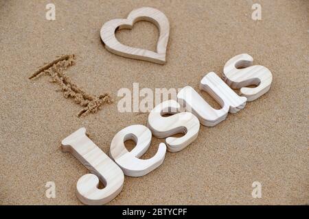 Holzbuchstaben bilden das Wort JESUS mit Herz auf einem Hintergrund von Strand Sand, Ich liebe Jesus, christliches Symbol, Vietnam, Indochina, Südostasien, wie Stockfoto