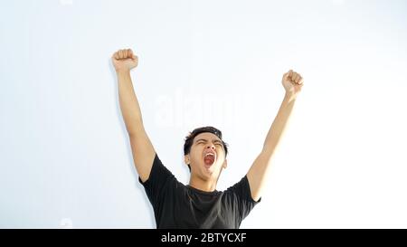 Erfolgreiche casual asiatischen Mann heben Arme nach dem Gewinn etwas Stockfoto