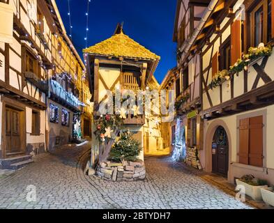 Fachwerkhäuser entlang der Rue du Rempart Sud, die nachts mit Weihnachtsschmuck geschmückt sind, Eguisheim, Elsass, Frankreich, Europa Stockfoto