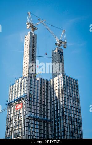 Krane auf der Oberseite von hohen Gebäuden während der Bauarbeiten am Bahnhof East Croydon, England. Stockfoto