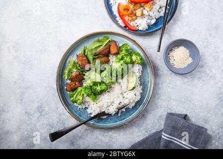 Vegane Teryaki Tempeh oder tempe buddha Schüssel mit Reis, gedämpftem Brokkoli, Spinat und Limette auf schwarzem Hintergrund. Gesunde Ernährung Stockfoto