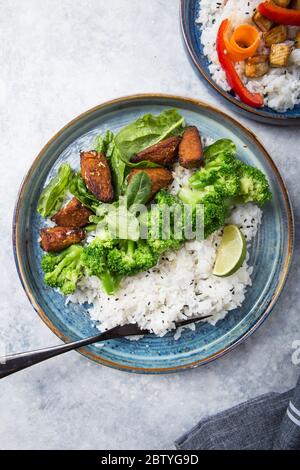 Vegane Teryaki Tempeh oder tempe buddha Schalen mit Reis, gedämpftem Brokkoli, Spinat und Limette auf schwarzem Hintergrund. Gesunde Ernährung Stockfoto