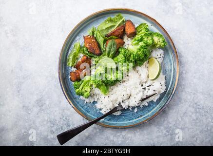 Vegane Teryaki Tempeh oder tempe buddha Schalen mit Reis, gedämpftem Brokkoli, Spinat und Limette auf schwarzem Hintergrund. Gesunde Ernährung Stockfoto