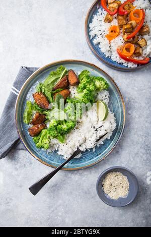 Vegane Teryaki Tempeh oder tempe buddha Schalen mit Reis, gedämpftem Brokkoli, Spinat und Limette auf schwarzem Hintergrund. Gesunde Ernährung Stockfoto