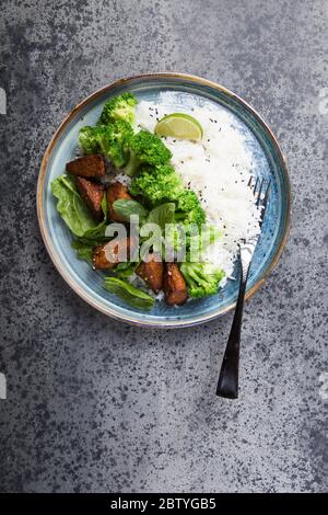 Vegane Teryaki Tempeh oder tempe buddha Schalen mit Reis, gedämpftem Brokkoli, Spinat und Limette auf schwarzem Hintergrund. Gesunde Ernährung Stockfoto