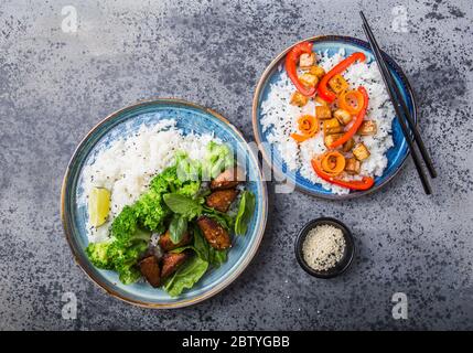 Vegane Teryaki Tempeh oder tempe buddha Schalen mit Reis, gedämpftem Brokkoli, Spinat und Limette auf schwarzem Hintergrund. Gesunde Ernährung Stockfoto