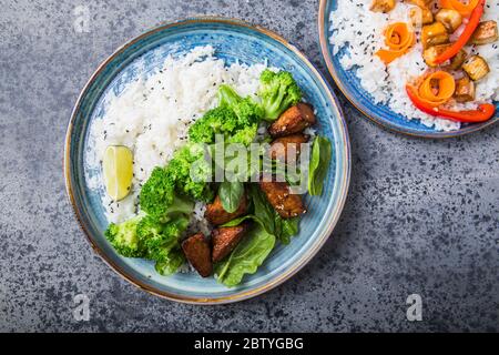 Vegane Teryaki Tempeh oder tempe buddha Schalen mit Reis, gedämpftem Brokkoli, Spinat und Limette auf grauem Hintergrund. Gesunde Ernährung Stockfoto