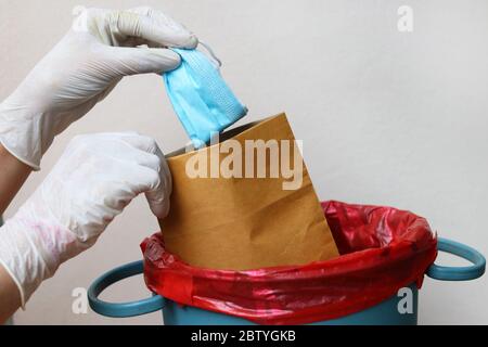 Hand mit Handschuhen Fallenlassen medizinische Maske in Beutel, bevor sie in Biohazard Autoklaven Beutel. Konzept für die Gesundheitsversorgung während Covid-19 Ausbruch . Stockfoto