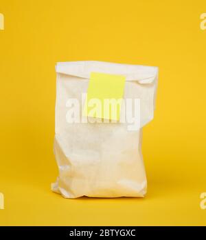Einweg-Lebensmittelbeutel aus Papier auf gelbem Hintergrund, Konzept der Lieferung und Bestellung von Lebensmitteln Stockfoto