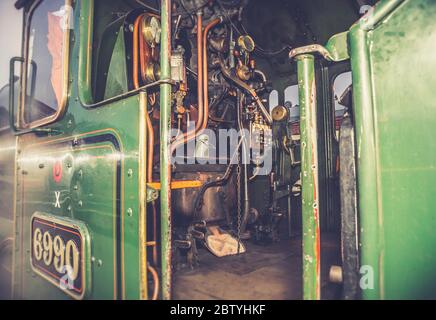 Atmosphärisch, Nahaufnahme der Zugfahrer-Bedienelemente, auf Fußplatte im Inneren Vintage UK Dampflokomotive Kabine bei Abend Wintersonne. Fahren mit Oldtimer-Zügen. Stockfoto