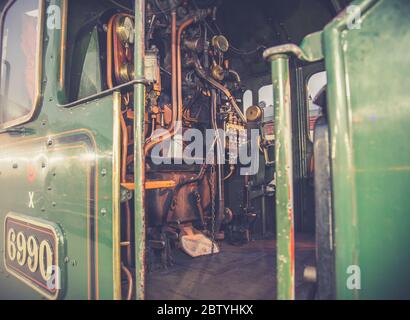 Atmosphärisch, Nahaufnahme der Zugfahrer-Bedienelemente, auf Fußplatte im Inneren Vintage UK Dampflokomotive Kabine bei Abend Wintersonne. Fahren mit Oldtimer-Zügen. Stockfoto