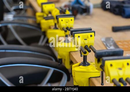 Viele Gelbe Visen sind auf der Arbeitsbank der Schule. Neue Griffe oder Klauen Laster repariert bei Holzbearbeitung Werkstatt. Stockfoto