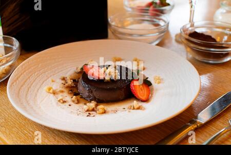 Lava-Schokoladenkuchen mit Eis und Erdbeere auf weißem Teller Stockfoto