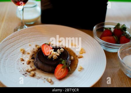 Lava-Schokoladenkuchen mit Eis und Erdbeere auf weißem Teller Stockfoto