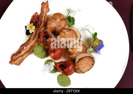 Jakobsmuscheln, Speck, Birnen- und Minzpüree werden auf einem weißen Teller in einem Restaurant serviert. Gourmet-Menü Display, Blick von oben und Platz für Kopie Stockfoto
