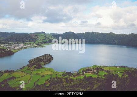 Herrlicher Blick auf die Lagoa Azul und das Dorf Sete Cidades vom Aussichtspunkt Miradouro do Cerrado das Freiras in Azoren, Portugal. Seen umgeben von grünen Feldern und Wald. Horizontales Foto. Stockfoto