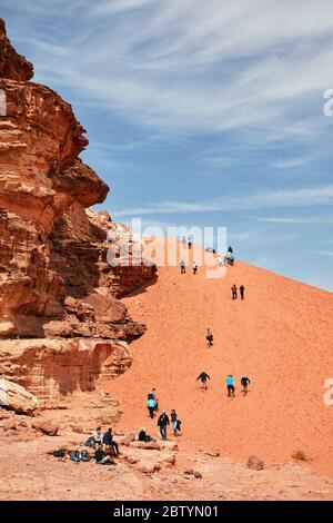 Touristen klettern Sanddüne in Wadi Rum, Aqaba, Jordanien Stockfoto