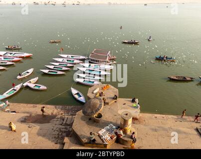 Varanasi, Uttar Pradesh, Indien - Februar 2015: Eine Luftaufnahme von hölzernen Ruderbooten auf dem Fluss Ganga neben den alten Ghats der alten Stadt. Stockfoto