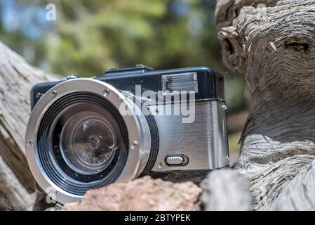 Schwarz-Silber-Lomography Fisheye II Kamera-Objektiv ruht auf einem Log während einer Pause beim Wandern Stockfoto