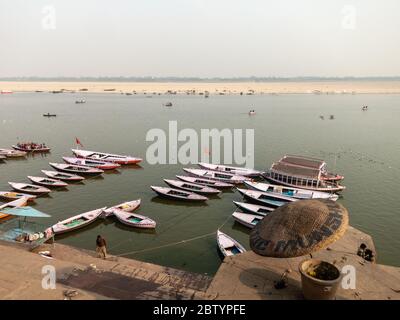 Varanasi, Uttar Pradesh, Indien - Februar 2015: Eine Luftaufnahme von hölzernen Ruderbooten auf dem Fluss Ganga neben den alten Ghats der alten Stadt. Stockfoto