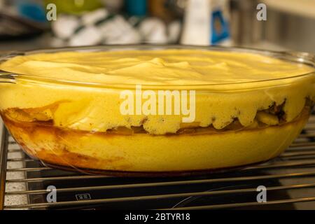 Sahne über den Äpfeln auf das Tablett gegeben, um den Apfelkuchen vorzubereiten. Stockfoto