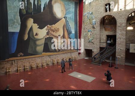 Die Besucher fotografieren neben dem unmarkierten Grab des spanischen surrealistischen Malers Salvador Dalí in der Haupthalle des Salvador Dalí Theaters und Museums in Figueres, Katalonien, Spanien. Im Hintergrund ist die riesige Kulisse zu sehen, die Salvador Dalí für das Ballett Labyrinth (1941) entworfen hat. Stockfoto