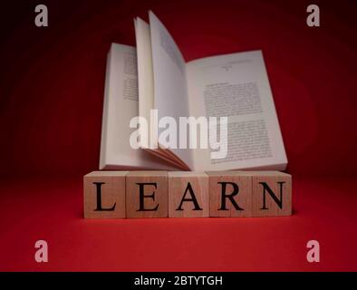 Das Wort lernen von Holzwürfeln. Der Hintergrund wurde in Rot und im Studio aufgenommen. Nahaufnahme. Stockfoto