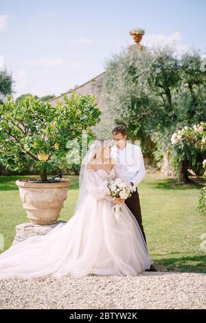 Hochzeitspaar im Garten. Der Bräutigam umarmt die Braut in der Nähe der Zitronenbäume. Hochzeit in Florenz, Italien, in einem alten Villa-Weingut. Stockfoto