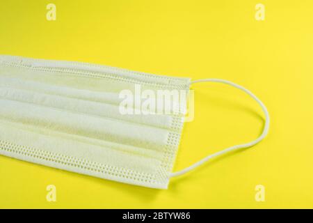 Nahaufnahme der weißen Gesichtsmaske auf gelbem Hintergrund. Schutz vor Coronavirus, Allergien, Grippe. Selektiver Fokus Stockfoto