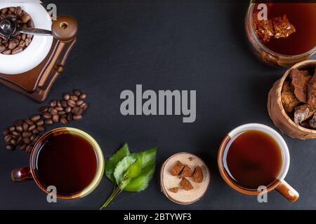 Zubereitung Chaga Pilz Kaffee. Keramikbecher, Glasgefäß mit Chaga-Getränk, Kaffeemühle, Chaga-Stücke und Kaffeemains auf schwarzem Hintergrund. Trend Stockfoto