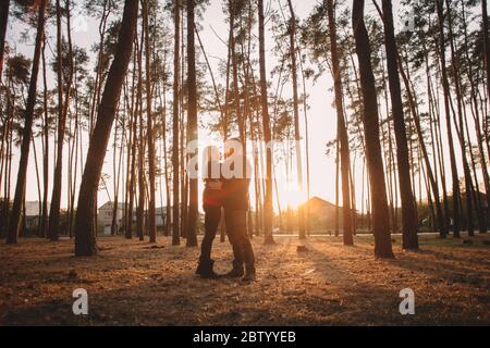 Seitenansicht des glücklichen jungen Paares in der Liebe einander von Angesicht zu Angesicht schauen, während romancing im Wald bei Sonnenuntergang Stockfoto