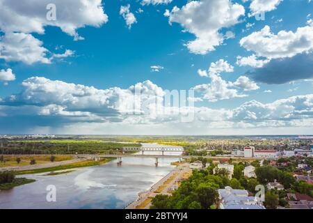 Stadtbild mit Brücke über den Fluss ein heller Tag mit blauem Himmel und Wolken über der Stadt. Viele Grünflächen und Wälder. Luftaufnahme Stockfoto