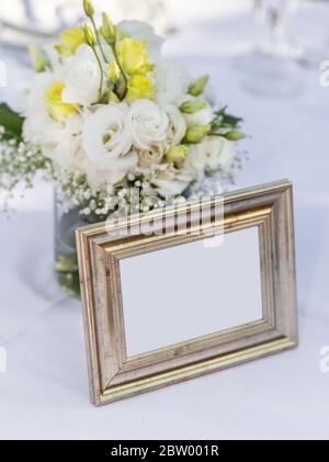 Brautstrauß in einem Glas neben einem alten, goldenen Bilderrahmen. Kopierbereich. Stockfoto
