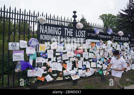 New York, NY, USA. Mai 2020. Ein Mann mit einer Maske geht an einem Denkmal für COVID-19-Opfer vorbei, das während der COVID-19-Pandemie am 28. Mai 2020 in New York an einem Zaun am Eingang zum Green-Wood-Friedhof hängt. Kredit: Bryan Smith/ZUMA Wire/Alamy Live News Stockfoto