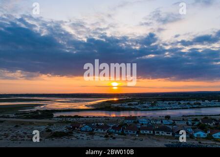 Wunderschöner Sonnenuntergang über dem Pagham Nature Reserve mit der Sonne, die zum Horizont sinkt und die Farben, die vom See reflektiert werden. Luftaufnahme. Stockfoto