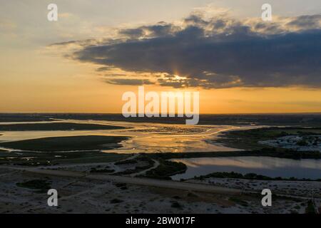 Wunderschöner Sonnenuntergang über dem Pagham Nature Reserve mit den Farben, die sich vom See spiegeln. Luftaufnahme. Stockfoto