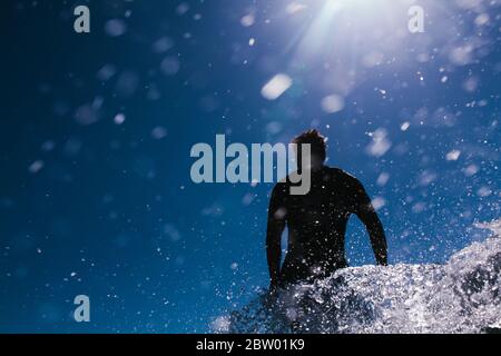 Surfer in Aktion in einem blauen Himmel mit Wasser gefüllt Tröpfchen Stockfoto