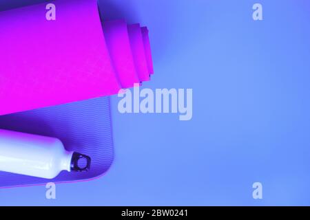 Leuchtend lila Yogamatte und eine Flasche Wasser. Stockfoto