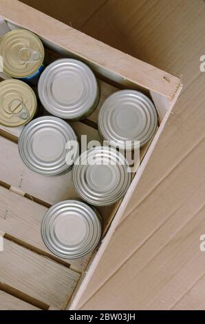 Blechdosen in einem Karton. Eine Vielzahl von Dosenfutter in vollen Blechdosen. Echtes Dosenessen. Blick von oben. Selektiver Fokus. Stockfoto
