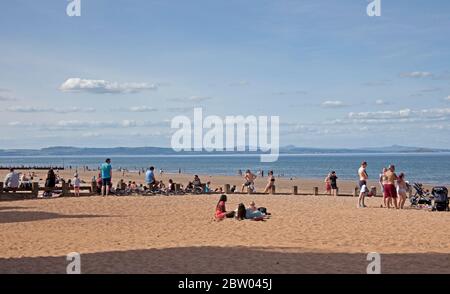 Portobello, Edinburgh, Schottland. 28 Mai 2020. 25 Grad am späten Nachmittag am Meer. Der Strand und die Promenade waren recht voll, die Polizei ging weiter, aber sie kümmerten sich nicht darum, mit jemandem über das Sitzen zu sprechen, da der schottische erste Minister einige der Einschränkungen für die schottische Öffentlichkeit lockert. Stockfoto