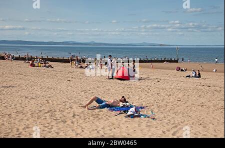 Portobello, Edinburgh, Schottland. 28 Mai 2020. 25 Grad am späten Nachmittag am Meer. Der Strand und die Promenade waren recht voll, die Polizei ging weiter, aber sie kümmerten sich nicht darum, mit jemandem über das Sitzen zu sprechen, da der schottische erste Minister einige der Einschränkungen für die schottische Öffentlichkeit lockert. Stockfoto