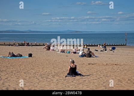 Portobello, Edinburgh, Schottland. 28 Mai 2020. 25 Grad am späten Nachmittag am Meer. Der Strand und die Promenade waren recht voll, die Polizei ging weiter, aber sie kümmerten sich nicht darum, mit jemandem über das Sitzen zu sprechen, da der schottische erste Minister einige der Einschränkungen für die schottische Öffentlichkeit lockert. Stockfoto